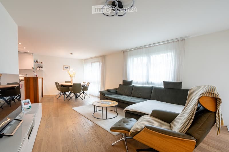 light walls, light wood floor, table and chairs in dining area, sofa, coffee table, TV stand, picture frame, mirror