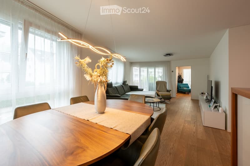 large windows, white walls, modern chandelier, wooden floor, modern furniture, dining table, chairs, living room, couch, center table, TV, pictures