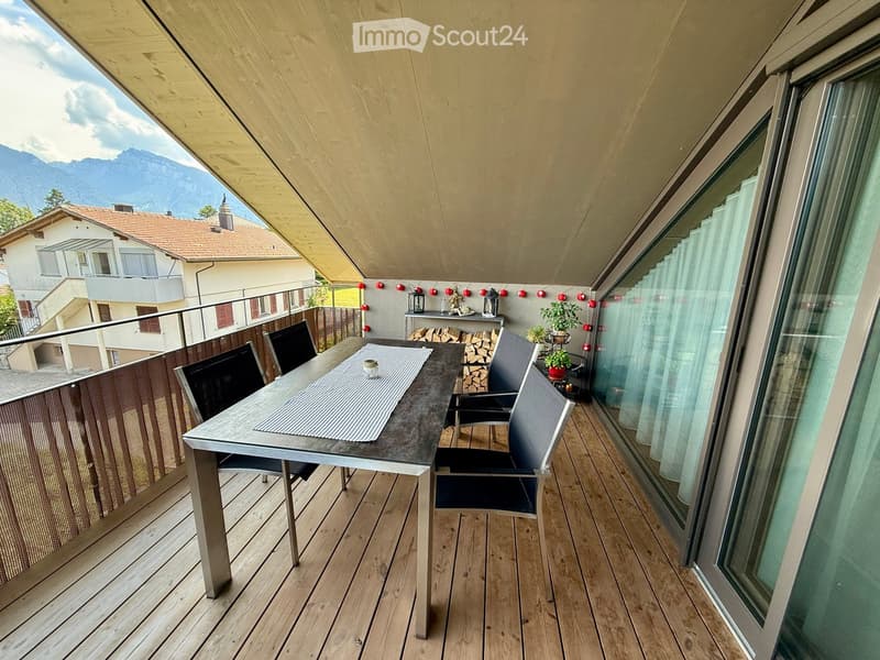 Balcony with wooden decking, a table with chairs, a small plant, and decorative lanterns.