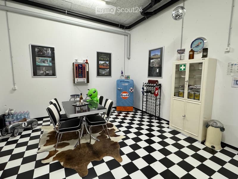 The room features a black and white checkered floor, a cowhide rug, a small table with chairs, a vintage-style refrigerator, a wine rack, a cabinet, and various decorative items including framed pictures and a toy alien.