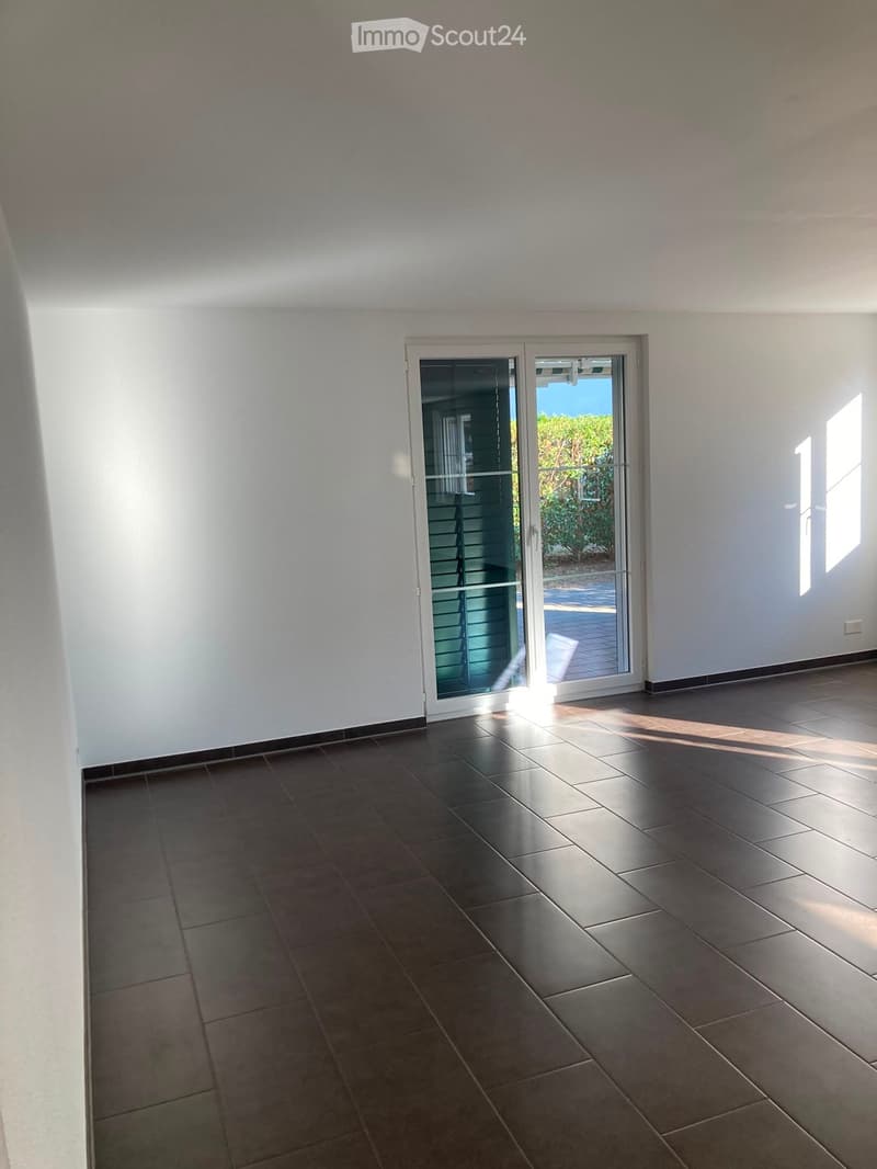 Empty room with tiled floor, white walls, and a large sliding glass door leading to an outdoor area.