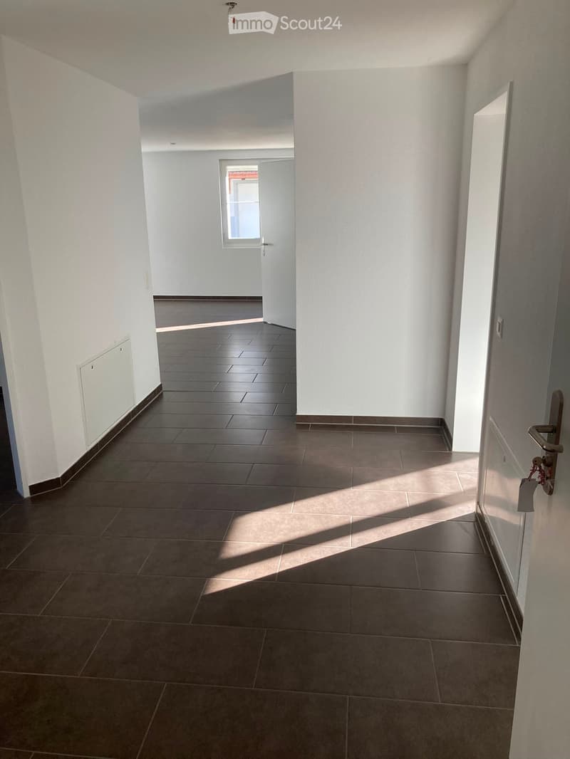 Empty hallway with tiled floor, white walls, and a door leading to another room.