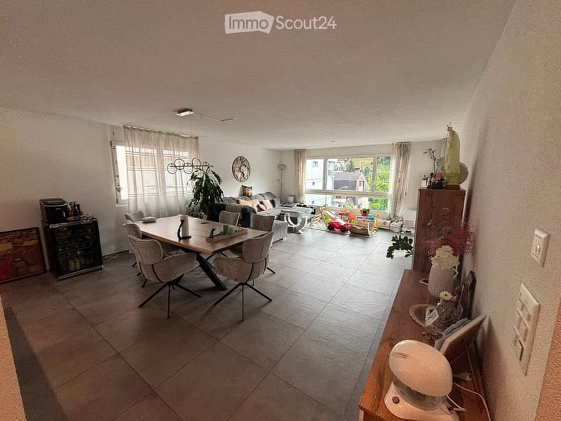 Open-plan living and dining area with a dining table, chairs, sofa, coffee table, and decorative items.