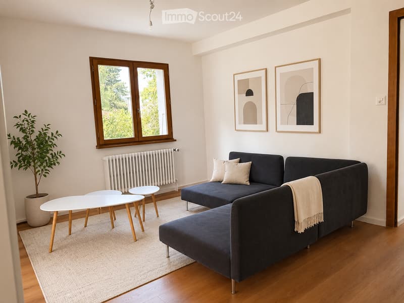 Modern living room with a dark blue sectional sofa, white coffee table, small white stools, a large plant in a pot, and two framed pictures on the wall. The room features wooden flooring and large windows with wooden frames.