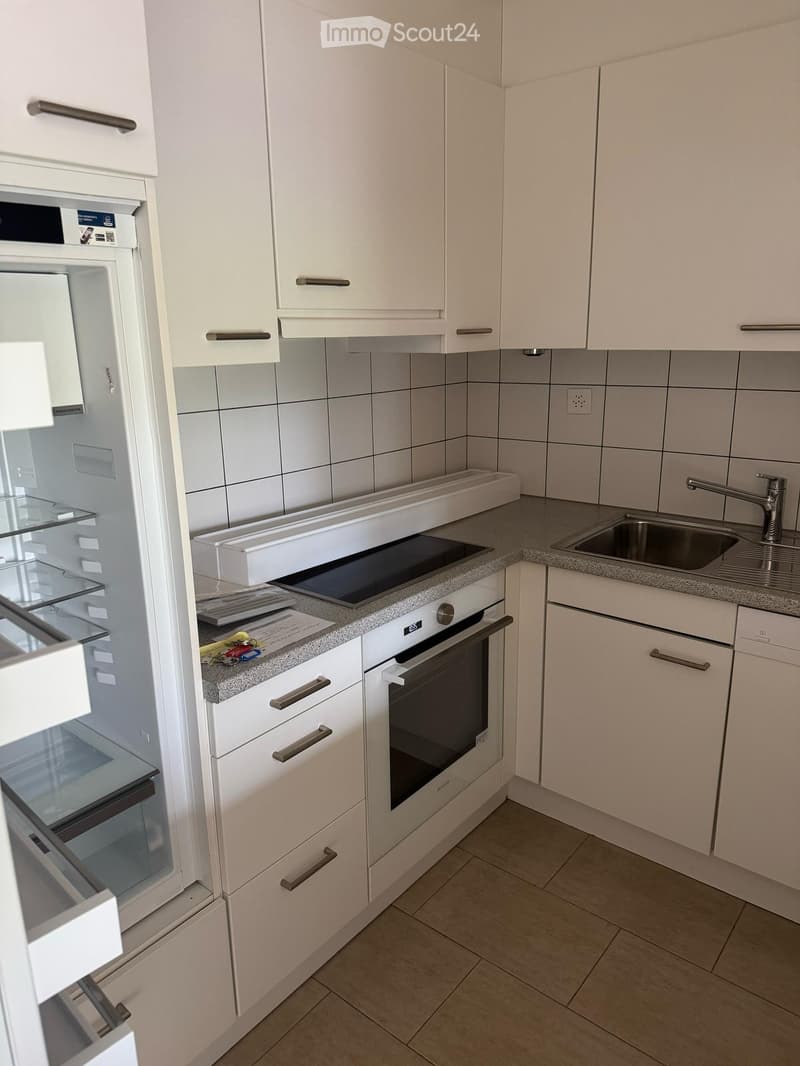 Modern kitchen with white cabinets, granite countertop, built-in oven, and stainless steel sink.
