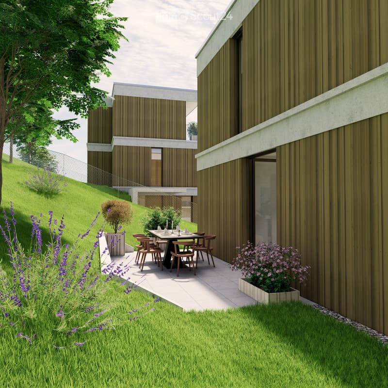 Outdoor patio area with a dining table and chairs, surrounded by greenery and flowers, adjacent to a modern house with wooden siding.