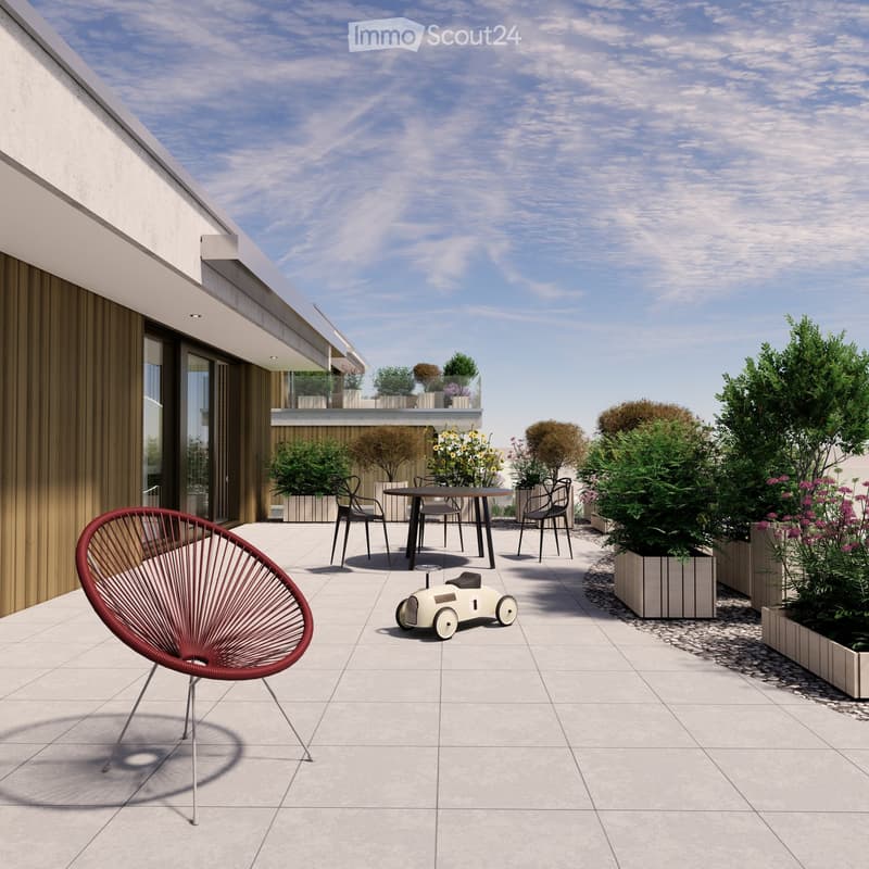 Modern rooftop terrace with tiled flooring, a red wireframe chair, a small table with four chairs, and a toy car. Potted plants and shrubs line the edge, with a view of neighboring balconies and a clear sky.