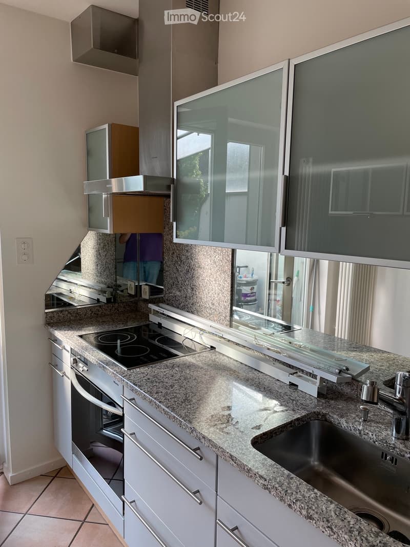 Modern kitchen with granite countertops, stainless steel appliances, and white cabinets.