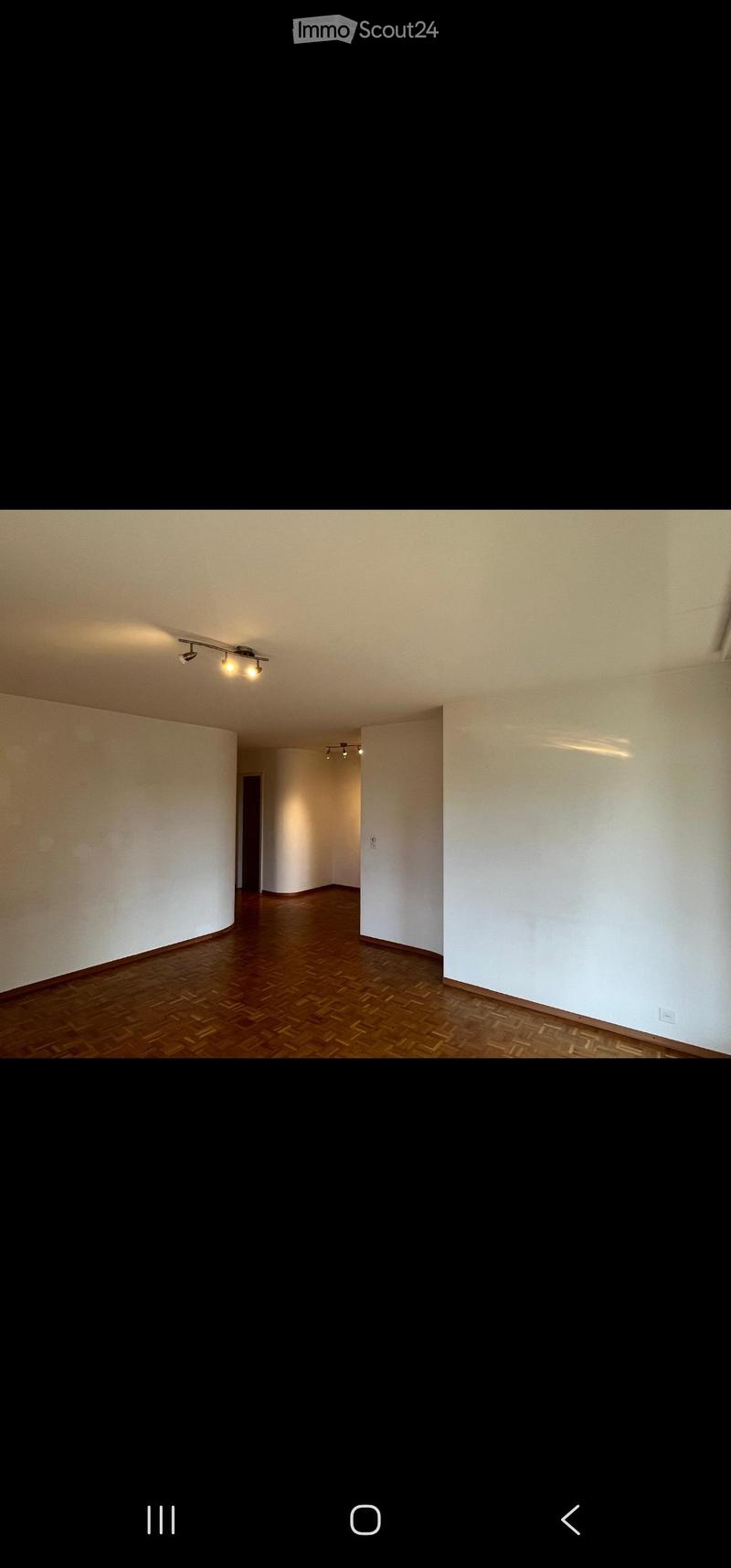 Empty room with wooden flooring and white walls, featuring recessed lighting fixtures on the ceiling.