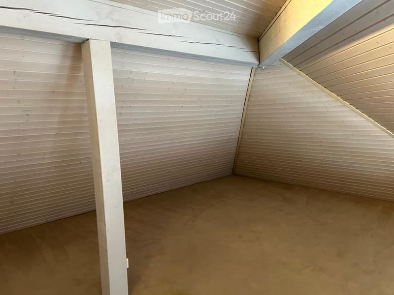 Empty room with wooden walls, a single support beam, and a concrete floor. No furniture or equipment is present.