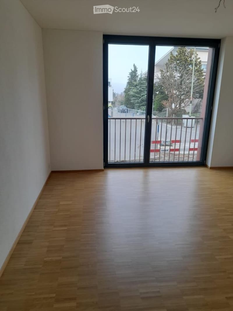 Empty room with wooden flooring and large sliding glass door leading to a balcony area.