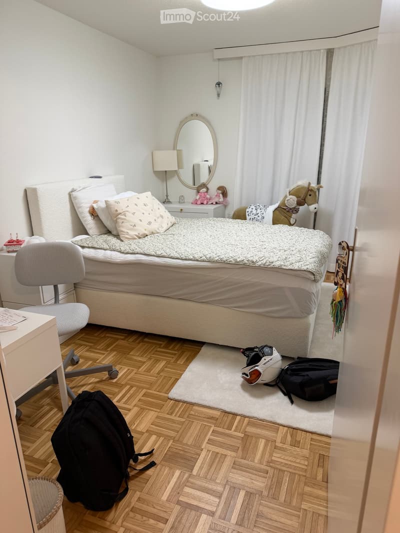 bedroom with a bed, chair, desk, lamp, mirror, toys, and a backpack