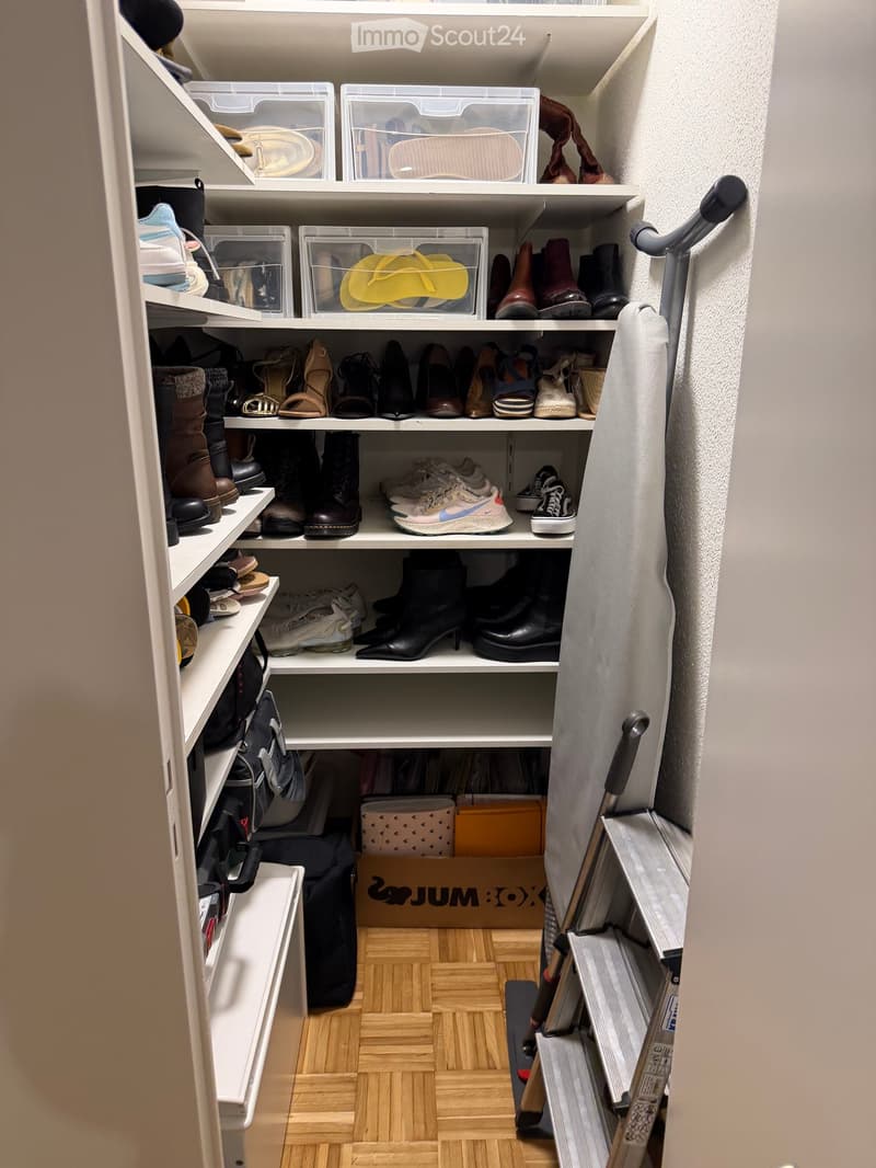 closet with storage boxes, shoes, black plastic bag, clothes hanging, ladder