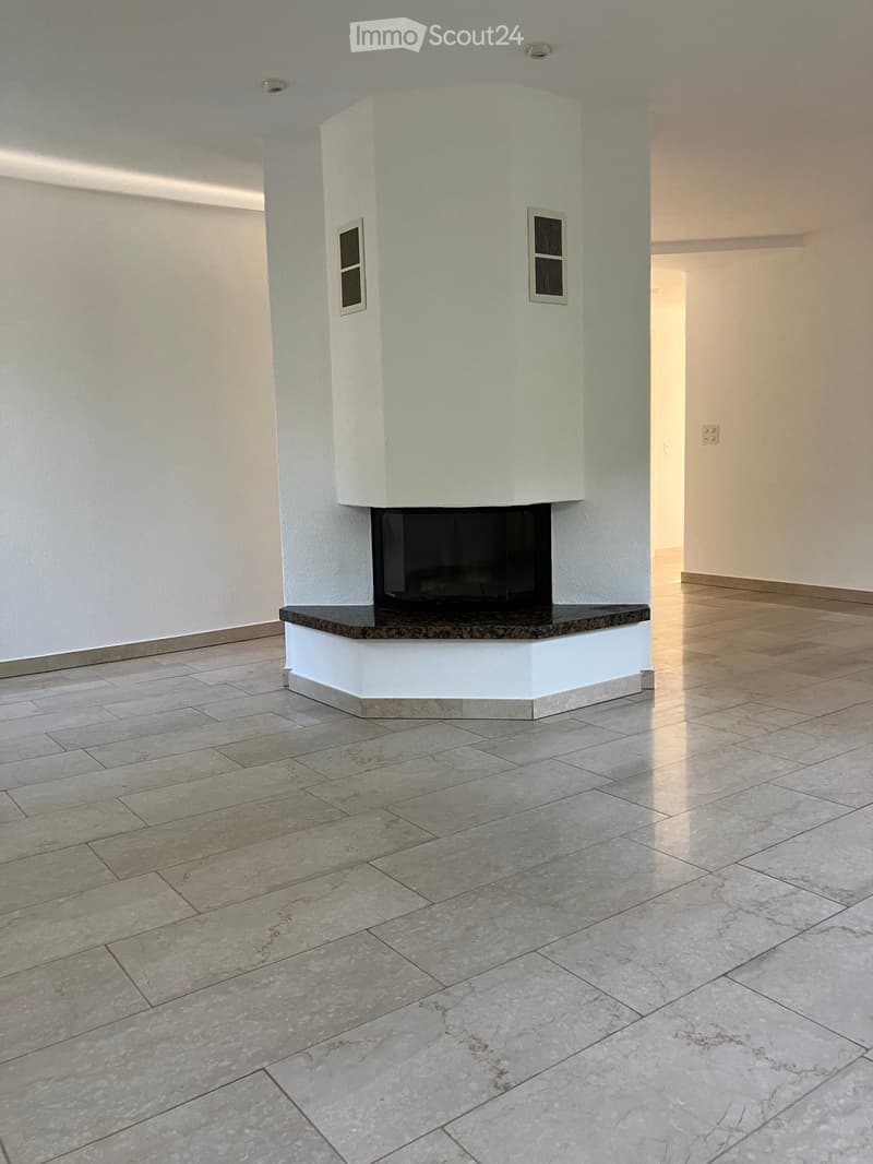 Empty hallway with tiled flooring and a built-in fireplace with a granite surround.