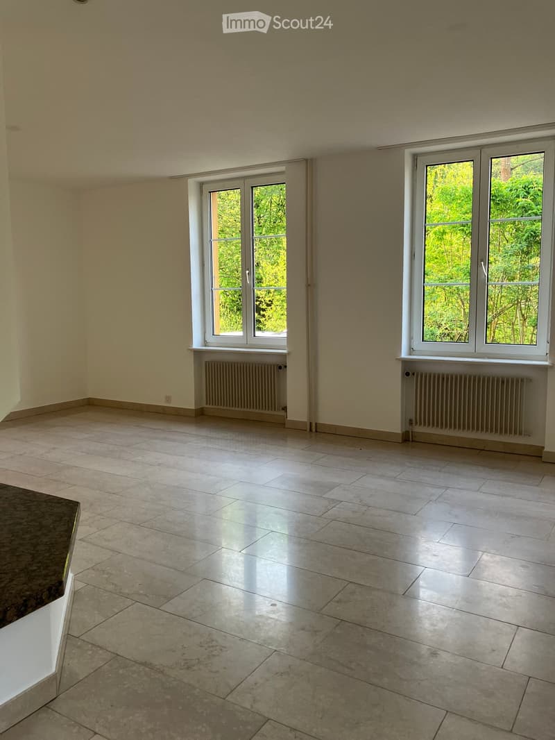 Empty room with light-colored tiled flooring, white walls, and large windows with white frames, allowing natural light to fill the space.