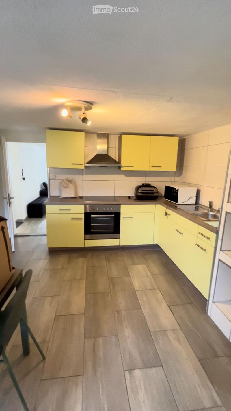 Modern kitchen with yellow cabinets, stainless steel appliances, and tiled floor.