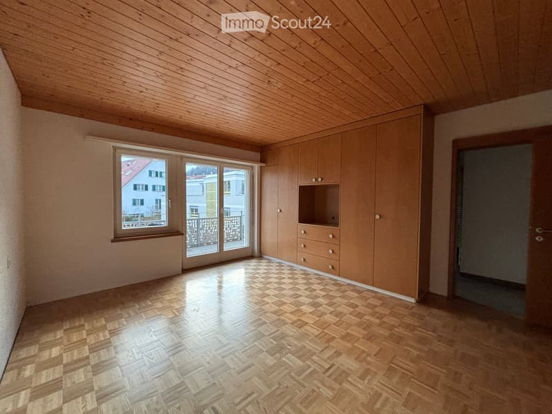 Empty room with wooden ceiling, herringbone wooden floor, built-in wooden cabinetry, large window, and sliding glass door leading to a balcony.