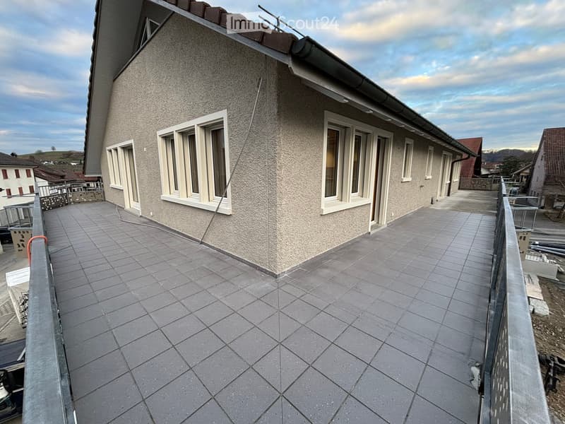 Balcony with tiled floor, metal railing, and access to the building’s exterior wall with windows.