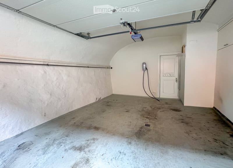 Empty garage with concrete floor, white walls, and a single door leading out.