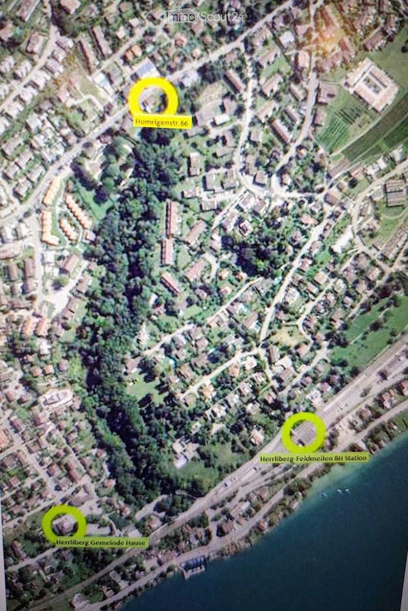 Aerial view of a residential area with buildings, roads, and green spaces. Key locations marked include Humrigestr. 56, Hernilberg Gemeinde Hause, and Hernilberg-Feldmeilen BH Station.
