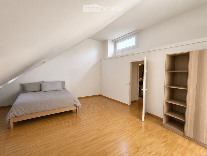Bright attic bedroom with wooden flooring, a single bed with grey bedding, a built-in wardrobe with shelves, and a skylight window.