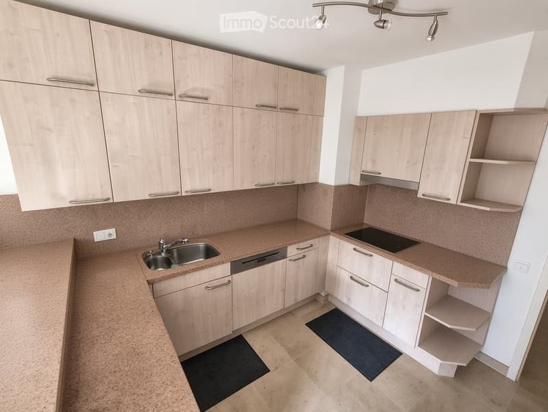 Modern kitchen with light wood cabinets, granite countertops, stainless steel sink and dishwasher, and built-in electric stove.