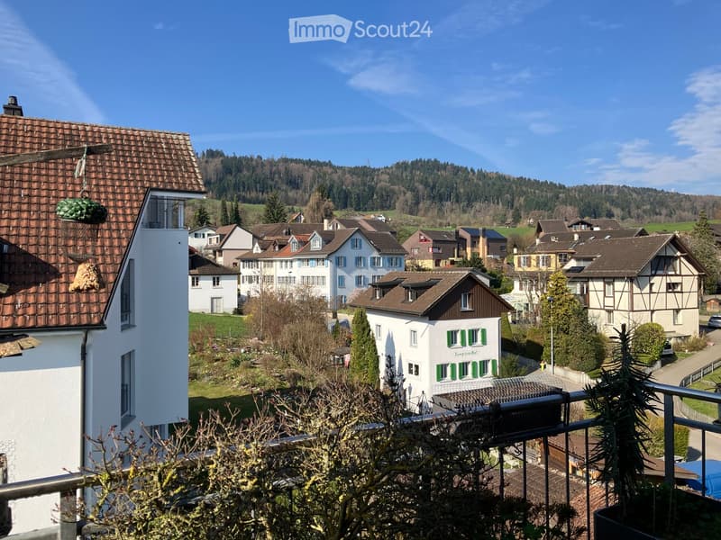 Building. View of a residential neighborhood with multiple houses, surrounded by greenery and hills in the background.