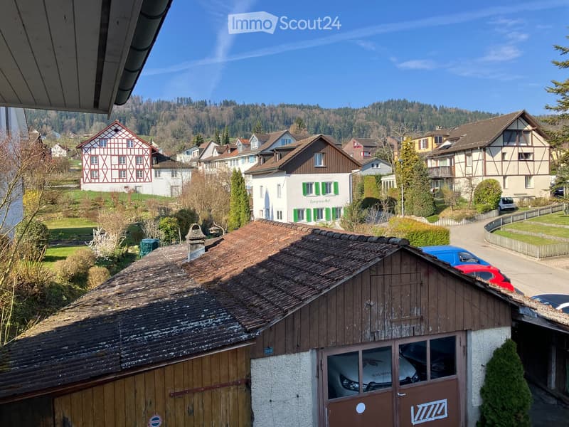 Building. View of a residential area with traditional houses, tiled roofs, and a mix of architectural styles, surrounded by greenery and a clear blue sky.