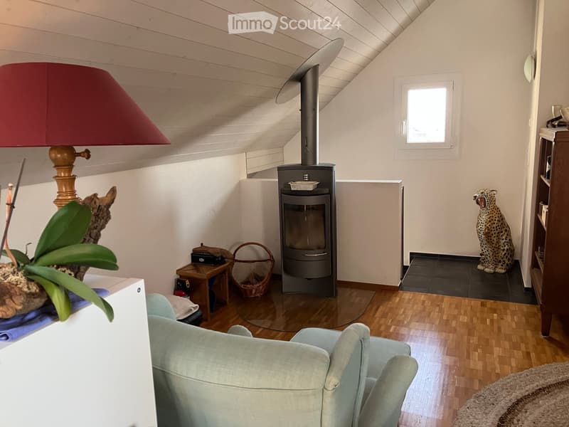 Furnished Room. Cozy living room with a fireplace, a light blue sofa, a table lamp with a red shade, a decorative plant, and a leopard statue on a shelf.