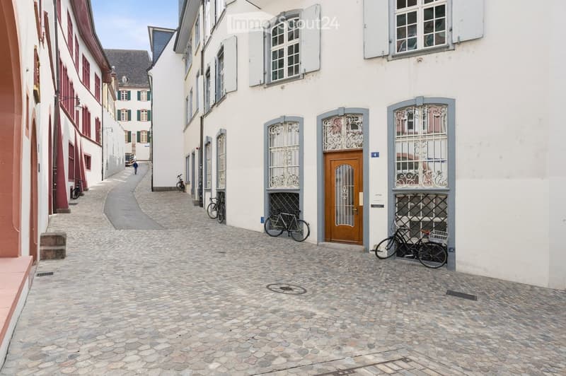 A narrow cobblestone alleyway lined with historic buildings, featuring bicycles parked along the sides and a wooden door with decorative metalwork.