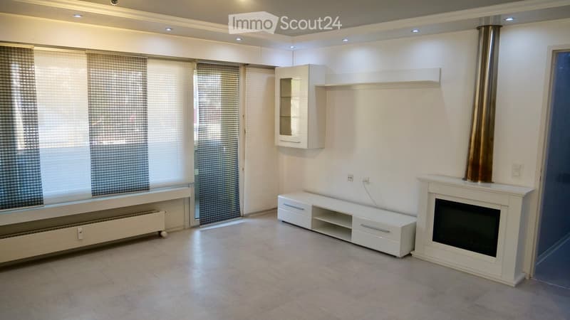 Modern living room with a fireplace, TV stand, white cabinet, and large windows with blinds.