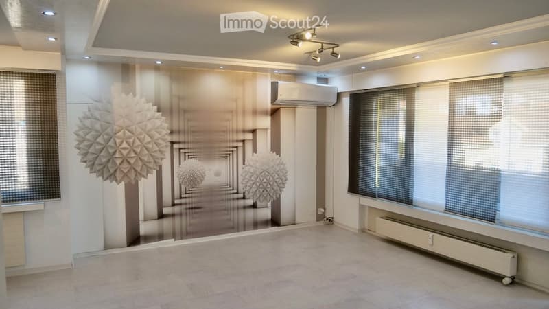 Empty room with large windows, modern lighting fixtures, and geometric wall art. No furniture or equipment present.