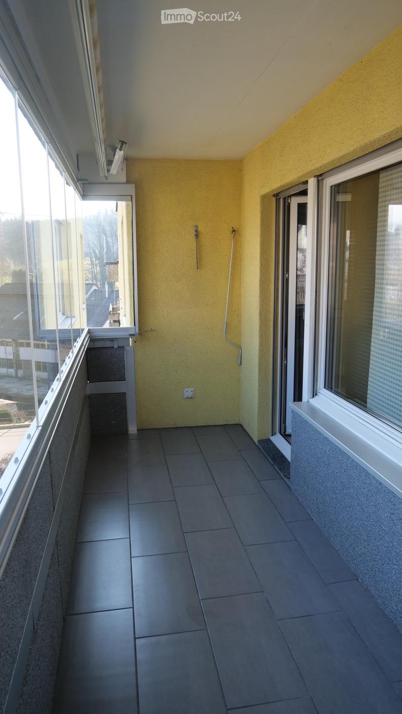Balcony with tiled floor, yellow walls, large windows, and a view of the surrounding area.