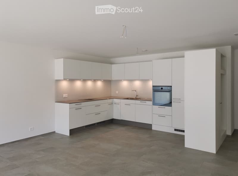 Modern kitchen with white cabinets, stainless steel sink, and built-in oven. The space features a tiled floor and recessed lighting.
