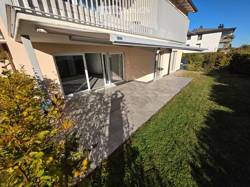 Modern house exterior with a balcony, patio area, and well-maintained garden.