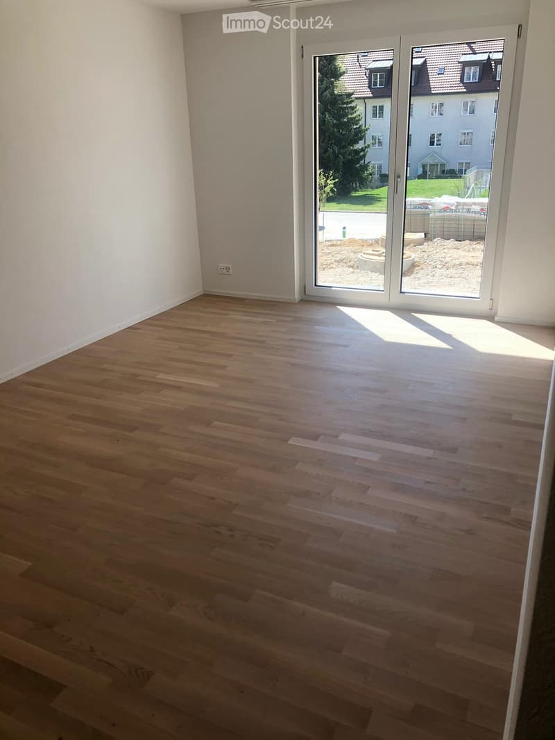 Empty room with light wooden flooring and large sliding glass doors leading to an outdoor area.