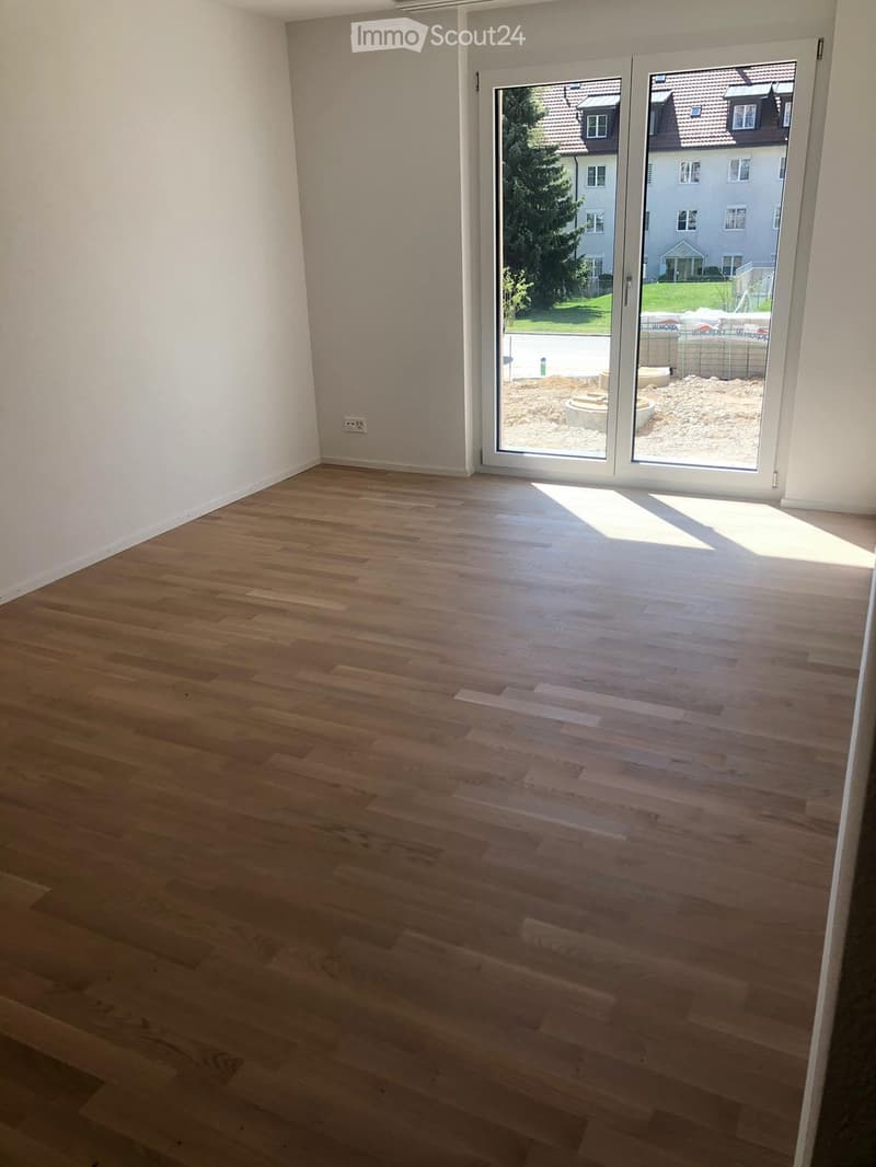 Empty room with light wooden flooring and large sliding glass doors leading to an outdoor area.
