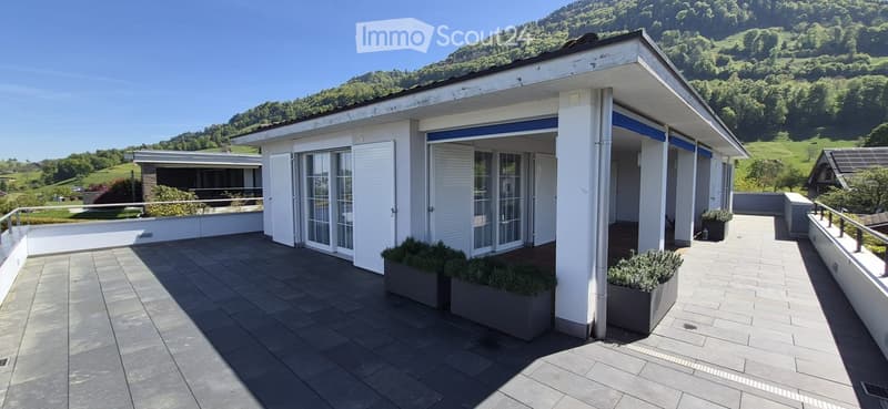 Spacious balcony with tiled flooring, white railings, and scenic mountain view in the background.