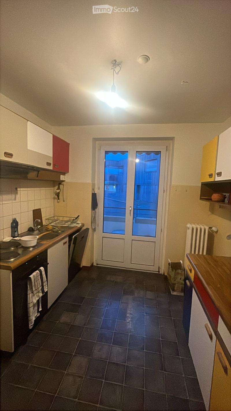 Kitchen with dark tiled floor, white and red cabinets, sink, oven, dishwasher, countertop, and a door leading outside.