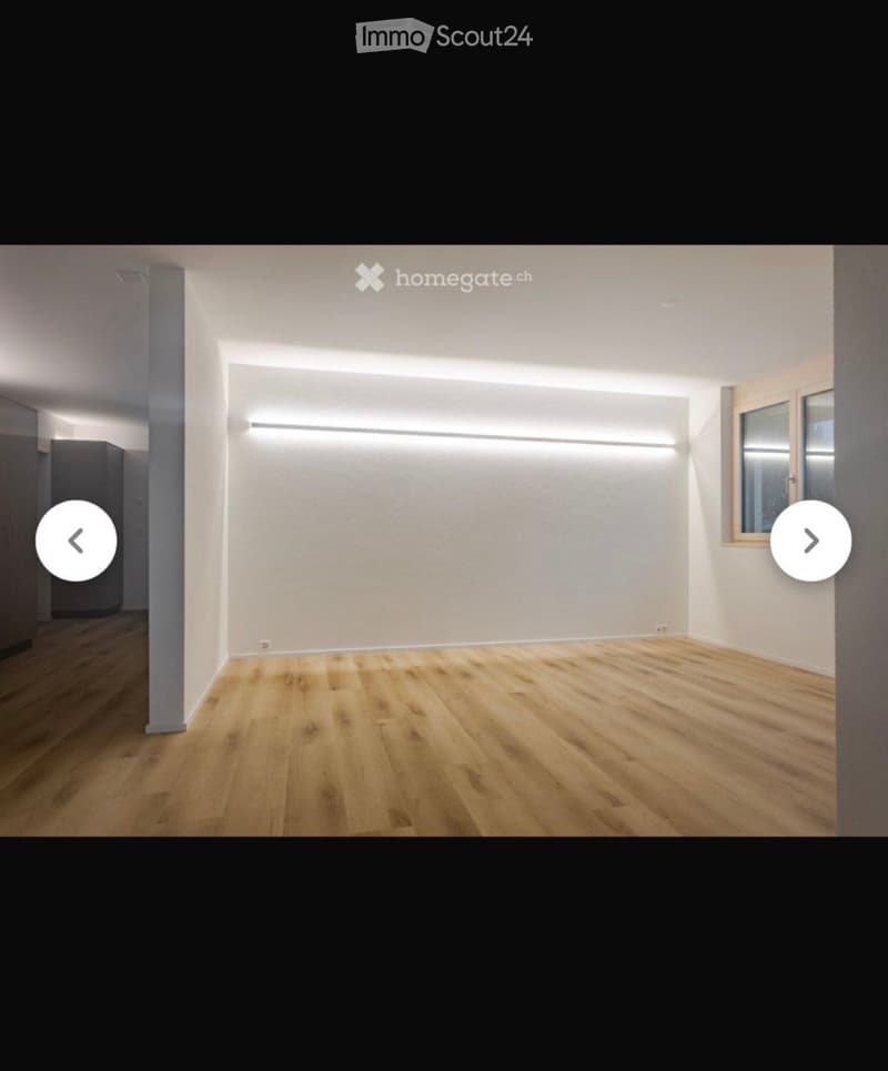 Empty room with light wooden flooring and white walls, featuring a large window and built-in LED lighting strips.