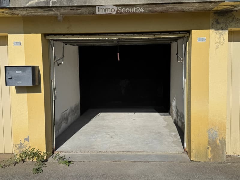 Open garage entrance with yellow walls, concrete floor, and a small mailbox on the left side.