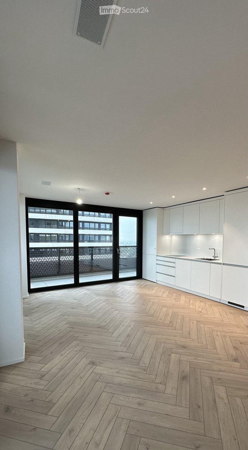 Empty room with wooden herringbone flooring, white cabinetry, and large sliding glass doors leading to a balcony.