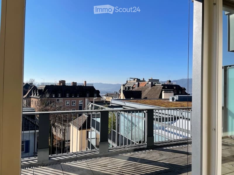 Balcony with metal railing, tiled floor, and a view of the cityscape and surrounding buildings.