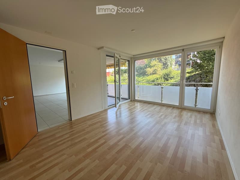 Empty room with wooden flooring, white walls, and large sliding glass doors leading to a balcony.