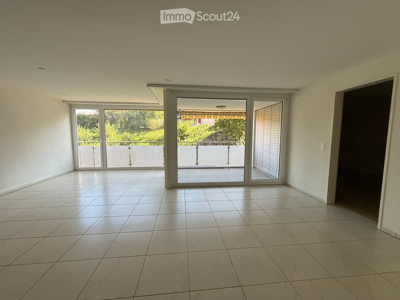 Empty room with white tiled flooring, large sliding glass doors leading to a balcony, and white walls.