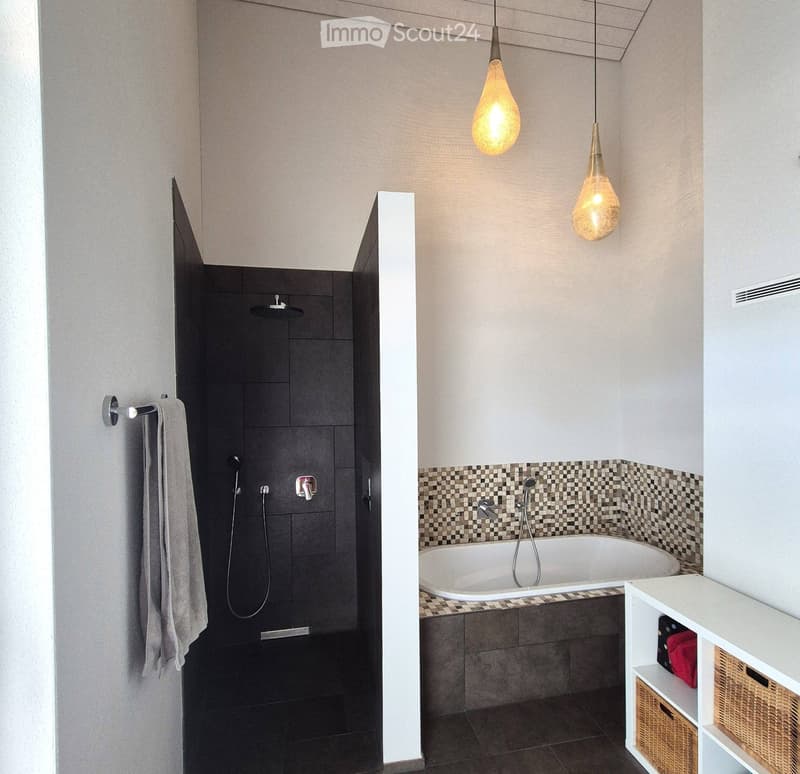 Modern bathroom with a bathtub, separate shower area, and a white storage unit with woven baskets. Features pendant lights and a checkered tile backsplash.