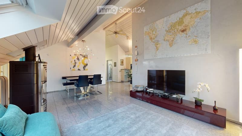 Modern living room with a blue sofa, coffee table, dining area with chairs and table, large television on a wooden stand, decorative map on the wall, and a fireplace.