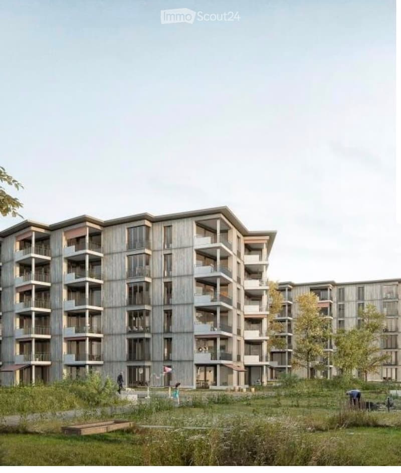 Modern multi-story residential building with balconies and large windows, surrounded by green space and trees.