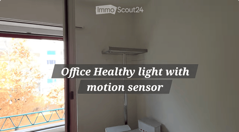 Empty room with a window and a motion sensor light fixture on the wall.