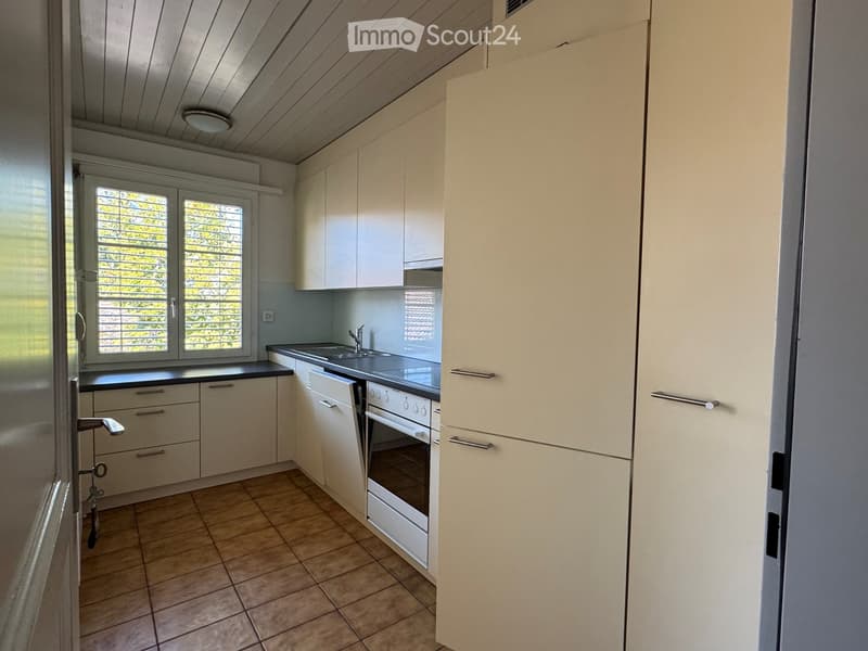 Modern kitchen with white cabinets, a sink, an oven, and tiled flooring.